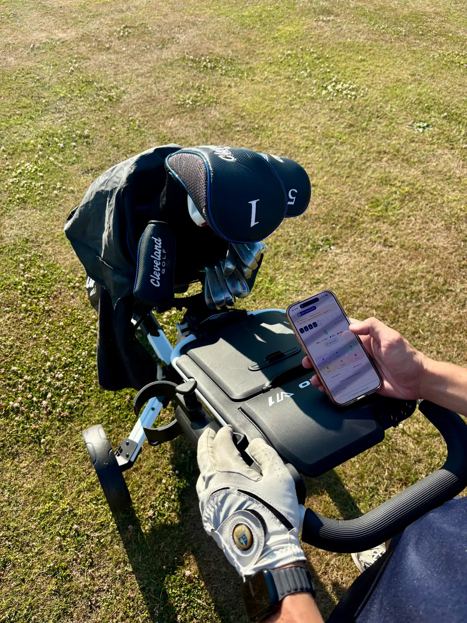 Le téléphone avec la carte de score Scluba posé sur le chariot de golf, à côté des clubs